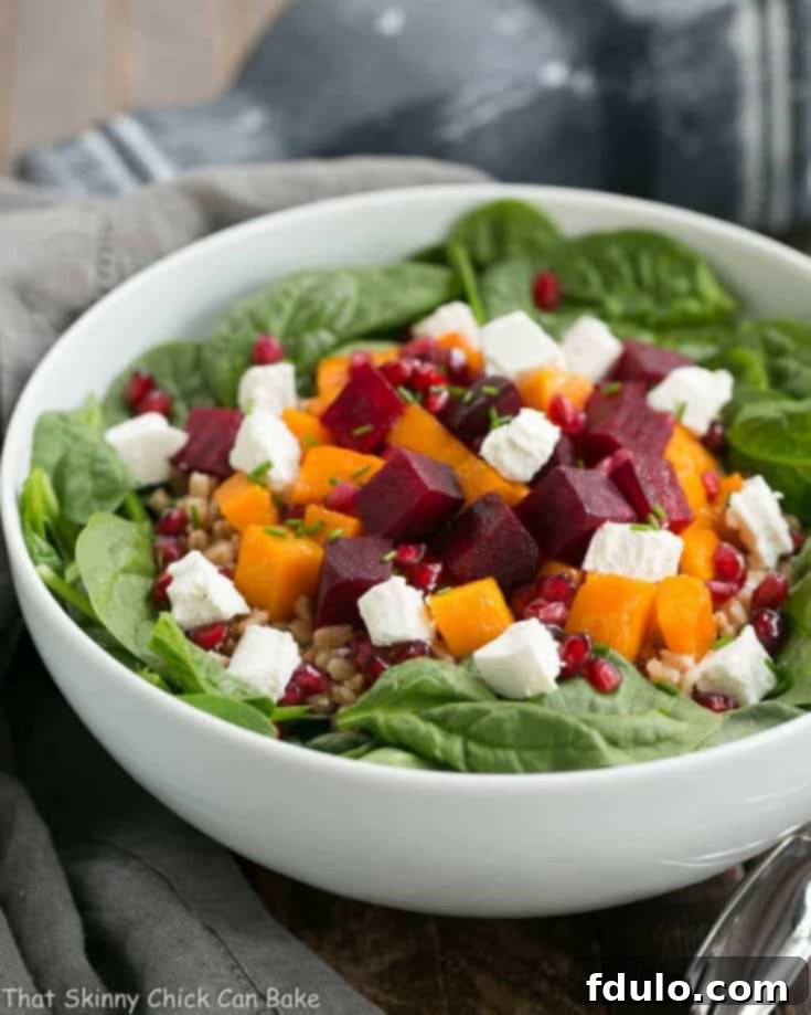 A stunning overhead shot of the Roasted Fall Vegetable Salad, featuring perfectly roasted beets and butternut squash, fresh spinach, farro, and goat cheese, with a maple balsamic vinaigrette.