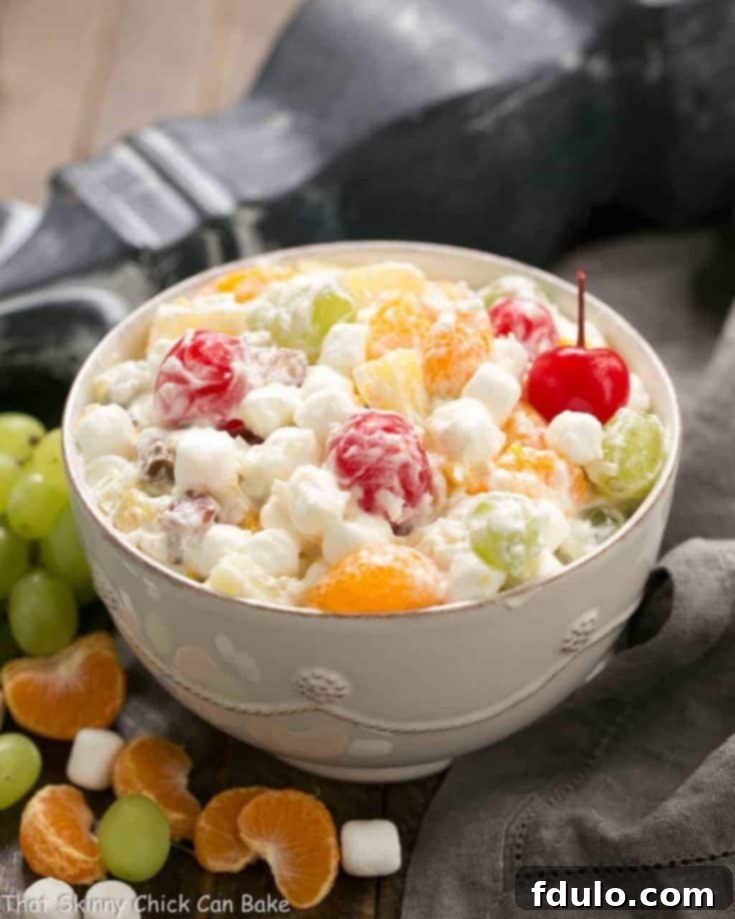 A bowl of creamy Ambrosia Salad garnished with fruit.