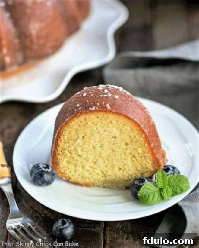Vanilla Bundt Cake - A simple, versatile butter cake that can be served in so many ways! A perfectly sliced Kentucky Butter Bundt Cake, garnished with fresh blueberries and a sprig of mint, presented on a pristine white dessert plate.