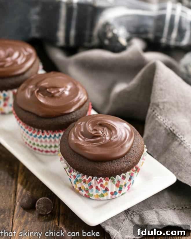 Cream Filled Chocolate Cupcakes lined up on a white ceramic tray.