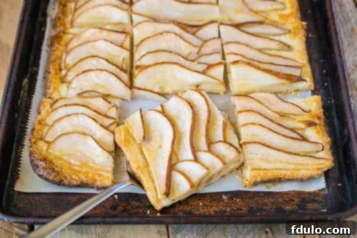 An elegant Easy Pear Tart, artfully arranged with fanned, juicy sliced pears and a glistening, golden brown finish, brushed with pear preserves.