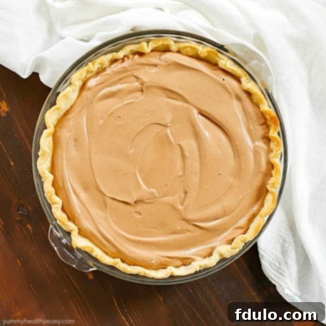 A generous slice of rich, creamy Mom's Easy Chocolate Pie, beautifully showcasing its decadent, smooth chocolate filling and flaky crust, ready for a taste.