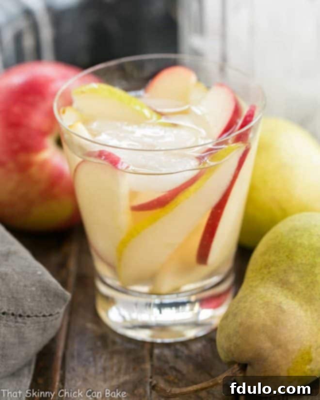 Apple Cider Sangria in a highball glass with ice, apple and pear slices