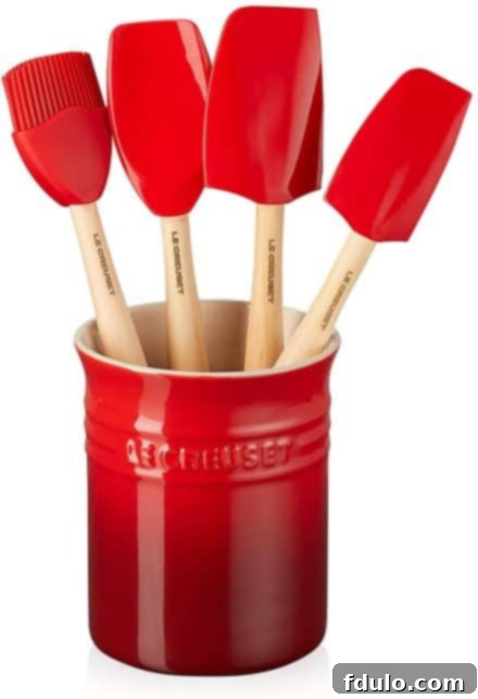 A red crock filled with colorful Le Creuset spatulas, adding a vibrant touch to the kitchen