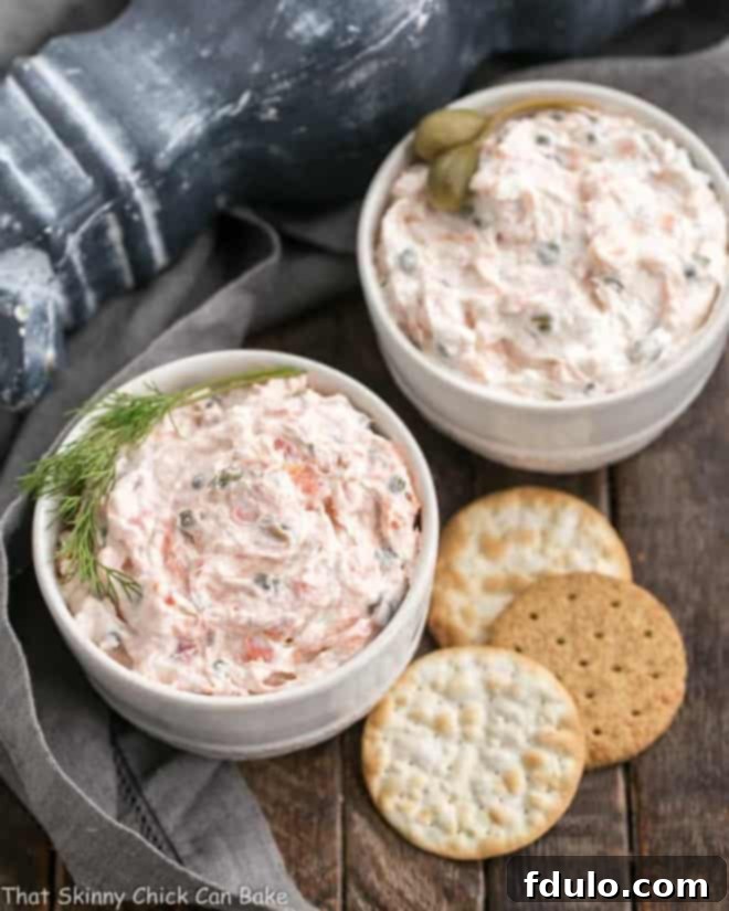 Two bowls of creamy smoked salmon dip with crackers on the side, ready for serving.