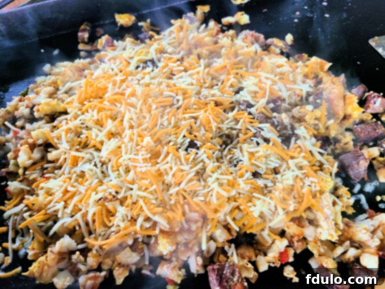Prime Rib Breakfast Hash cooking on blackstone with cheese on it