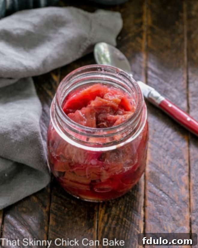 Rhubarb compote in a glass canning jar with a red handle spoon