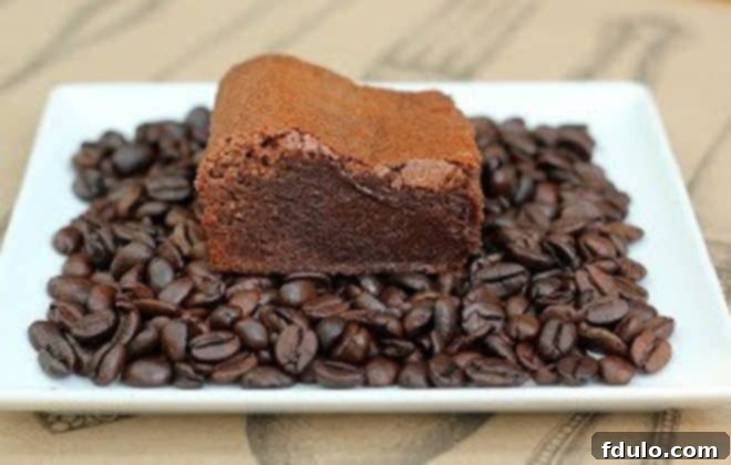 Vintage photo of Kahlua Brownies on a white plate covered with coffee beans, offering a nostalgic look at the original recipe presentation.