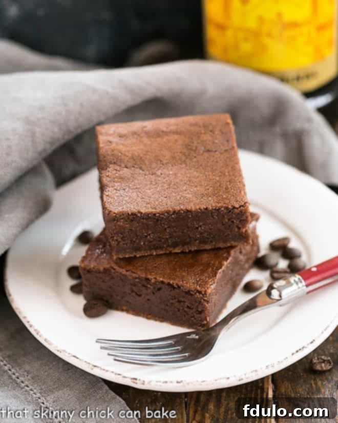 Beautifully cut Kahlua brownies on a white plate with a red handled fork, ready for serving.