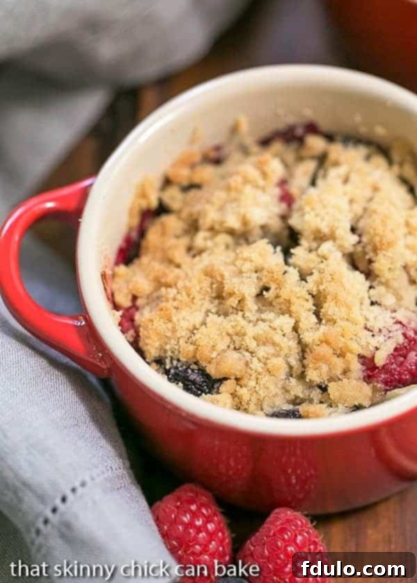 Individual Berry Crisps - A marvelous summer berry treat topped with a brown sugar streusel Overhead view of an Individual Berry Crisp in a red ceramic baking dish.