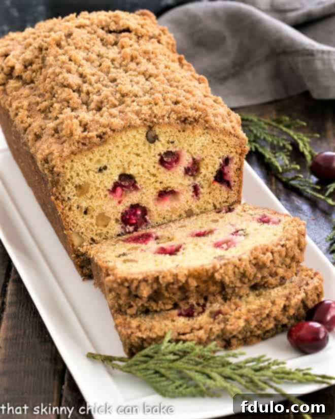 Streusel Topped Cranberry Orange Walnut Bread slices on a white platter, showcasing its moist texture and vibrant cranberries.