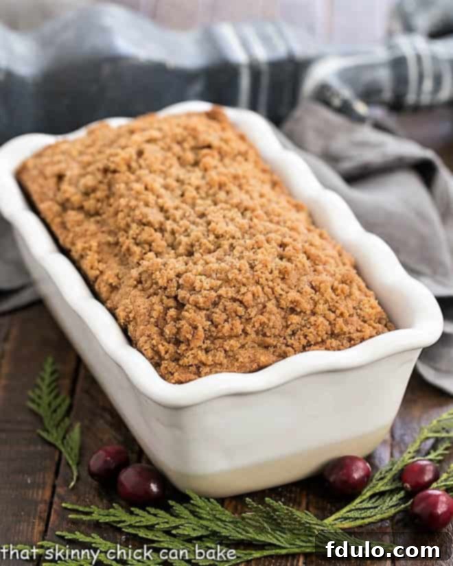 A whole Streusel Topped Cranberry Bread loaf in a white ceramic loaf pan, golden brown and inviting.