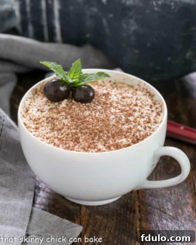 Decadent Chocolate Tiramisu 4 A teacup filled with chocolate tiramisu garnished with cocoa and espresso beans and a sprig of mint, ready to be enjoyed.