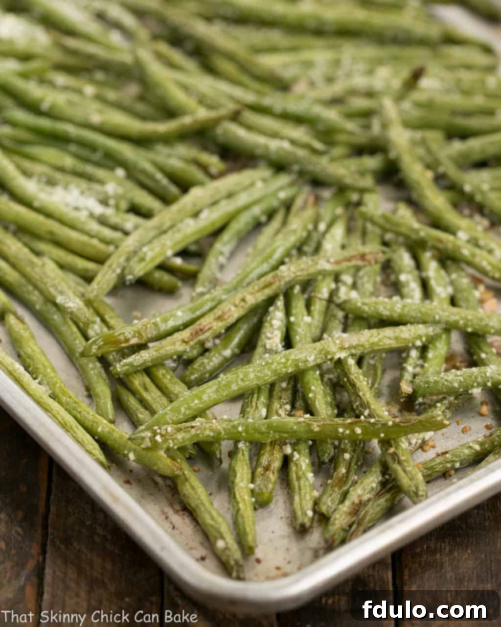 Garlic Parmesan Roasted Green Beans spread evenly on a sheet pan, ready for roasting.