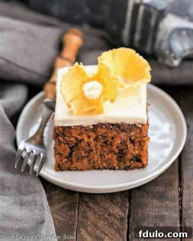 Slice of the best carrot cake on a round white plate, garnished with a pineapple flower