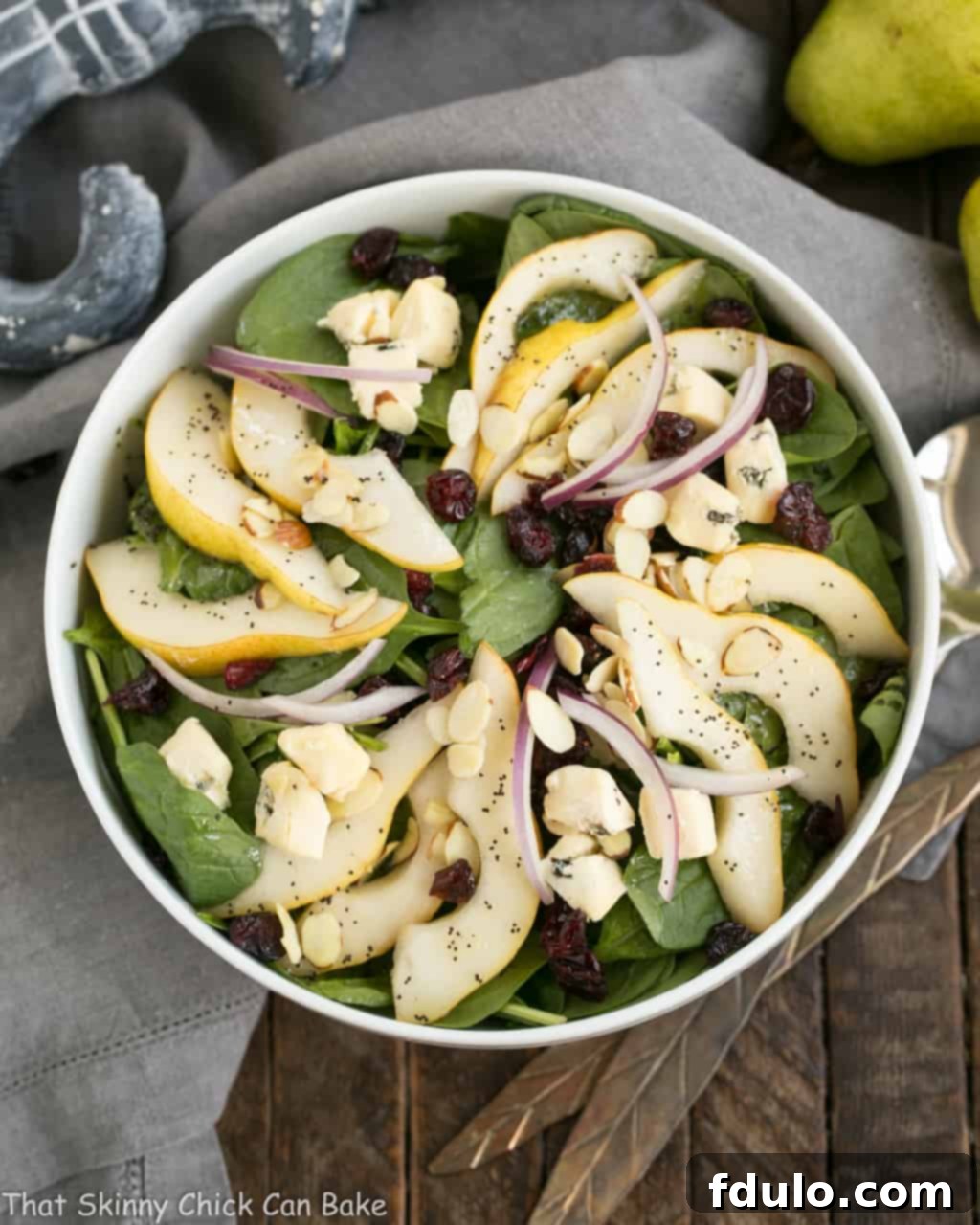 Jeweled Pear and Blue Cheese Spinach Salad 3 A close-up of a beautifully arranged Spinach Pear Salad with Cranberries and Blue Cheese, showcasing the vibrant ingredients.