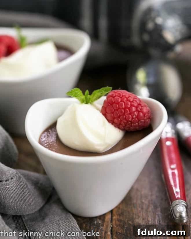 Chocolate Pots de Crème topped with white chocolate cream, fresh raspberries, and chocolate shavings.