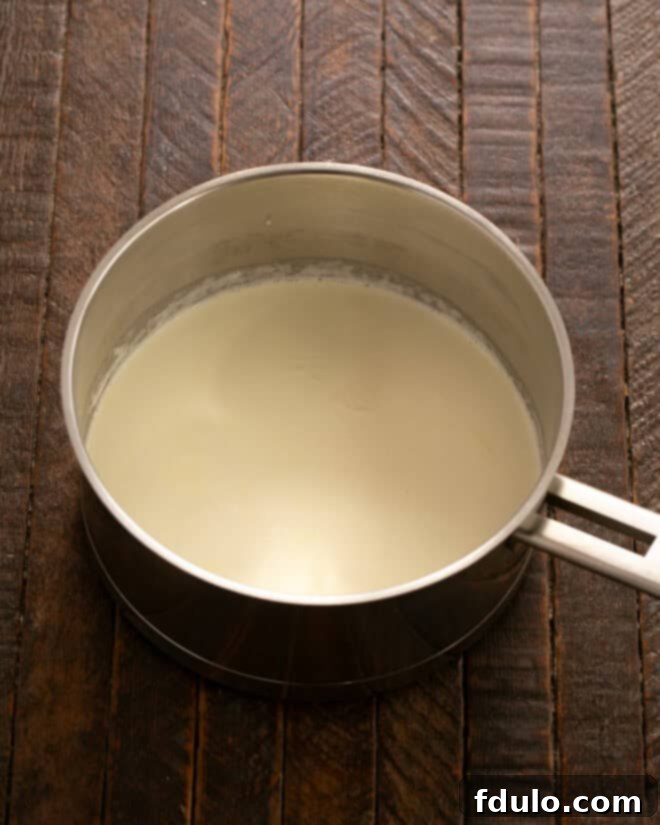 Heavy cream simmering in a saucepan on the stove.