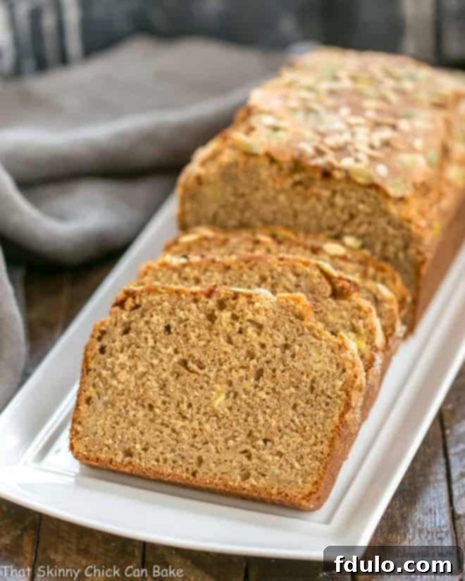 Seed-Topped Whole Wheat Banana Bread slices on a white tray, showcasing its wholesome texture and golden seeds.