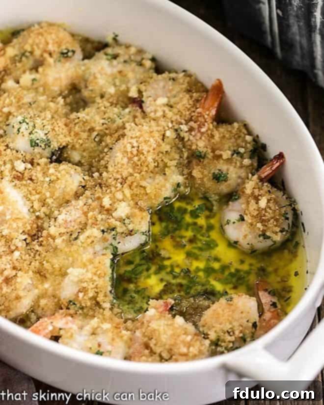 Baked Garlic Shrimp - a flavorful and easy-to-make casserole dish featuring tender shrimp in a spicy garlic butter sauce, finished with a crispy breadcrumb and Parmesan topping. A close-up view of Baked Garlic Shrimp simmering in a shallow casserole dish, highlighting the golden-brown breadcrumb topping and bubbling garlic butter.