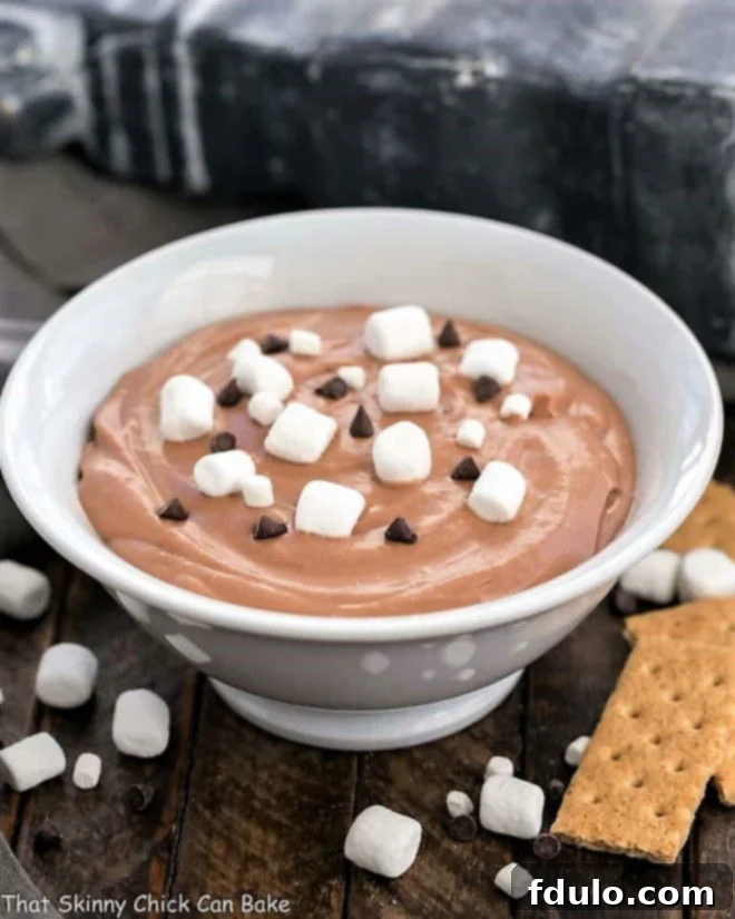 Easy S'mores Dessert Dip in a white bowl topped with mini marshmallows and chocolate chips.