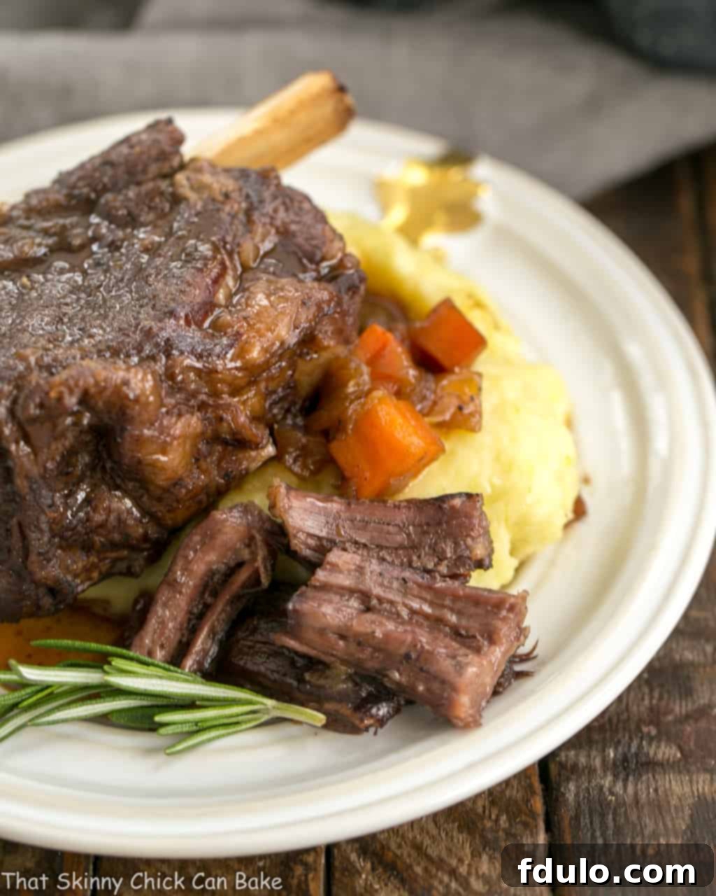 A close-up of tender Instant Pot Beef Short Ribs, beautifully browned and coated in a rich, dark sauce, served alongside creamy mashed potatoes on a white plate.
