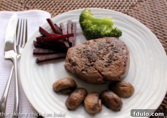 Steak au Poivre Recipe - a perfect pan-seared beef tenderloin with a decadent Cognac cream sauce Pepper Steak on a white plate with sautéed mushrooms, vibrant beets, and crisp broccoli, offering a complete and colorful meal.
