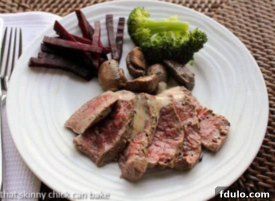 Bistrot Paul Bert Pepper Steak - exquisite pan-seared beef tenderloin with a luxurious Cognac cream sauce Pepper steak elegantly sliced and fanned out on a white plate, generously drizzled with the rich and creamy pan sauce.