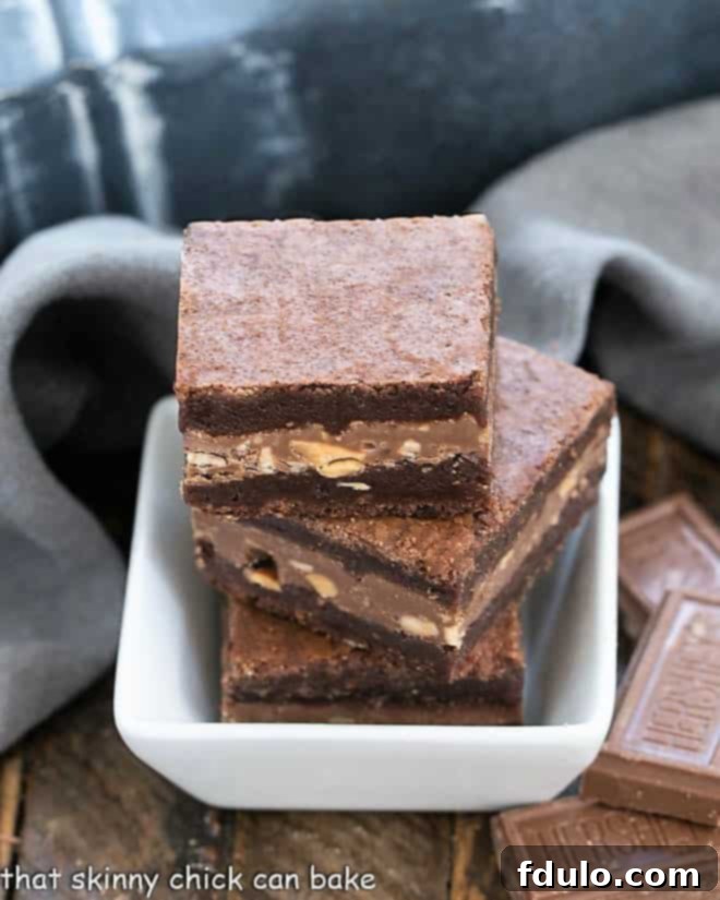 Three decadent Symphony Toffee Brownies, showcasing their fudgy interior and gooey melted chocolate toffee filling, artfully arranged in a small square white bowl, ready for indulgence.