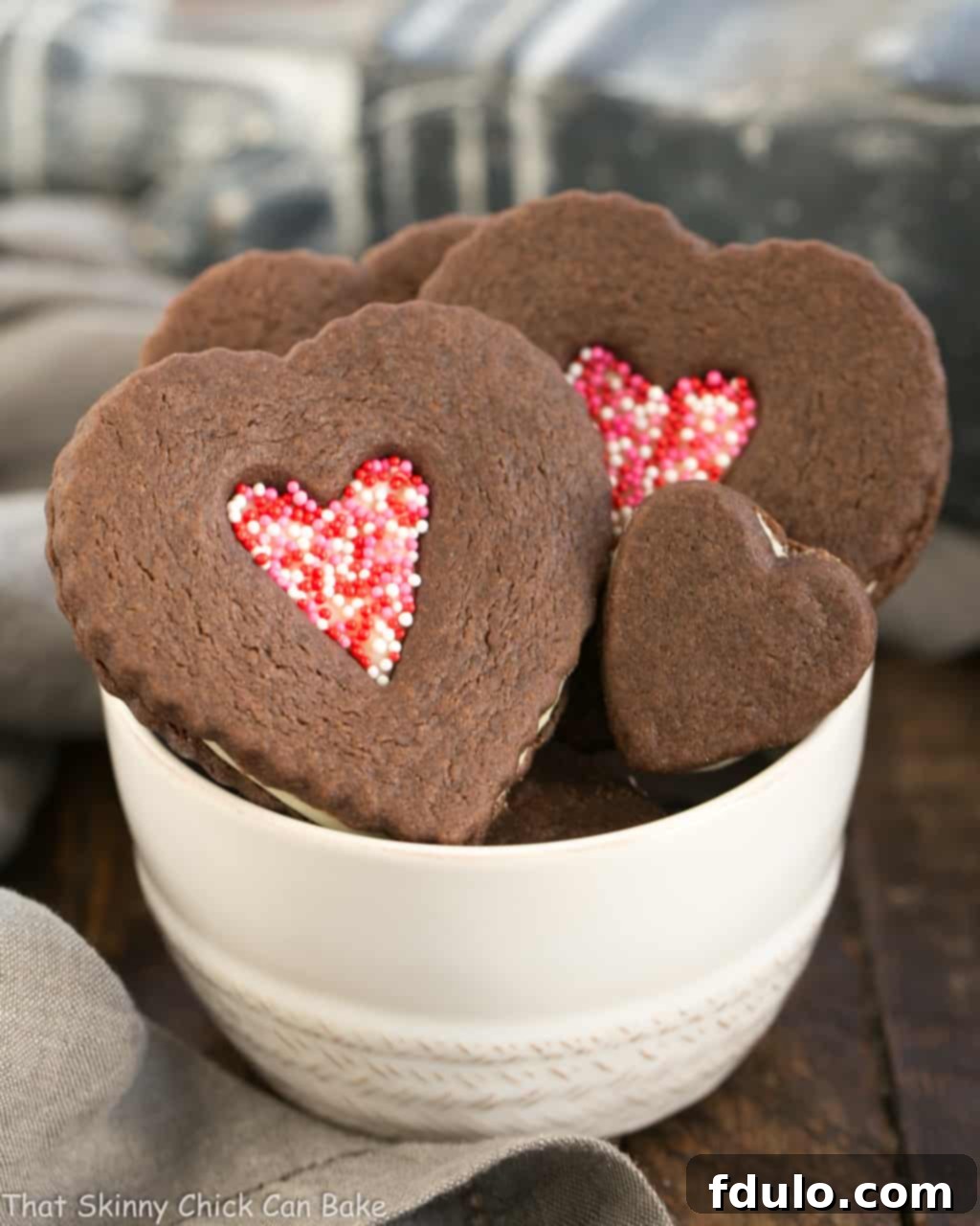 Decadent Chocolate Heart Sandwich Cookies in a pristine white bowl, showcasing their rich color and creamy white ganache filling, perfect for Valentine's Day.