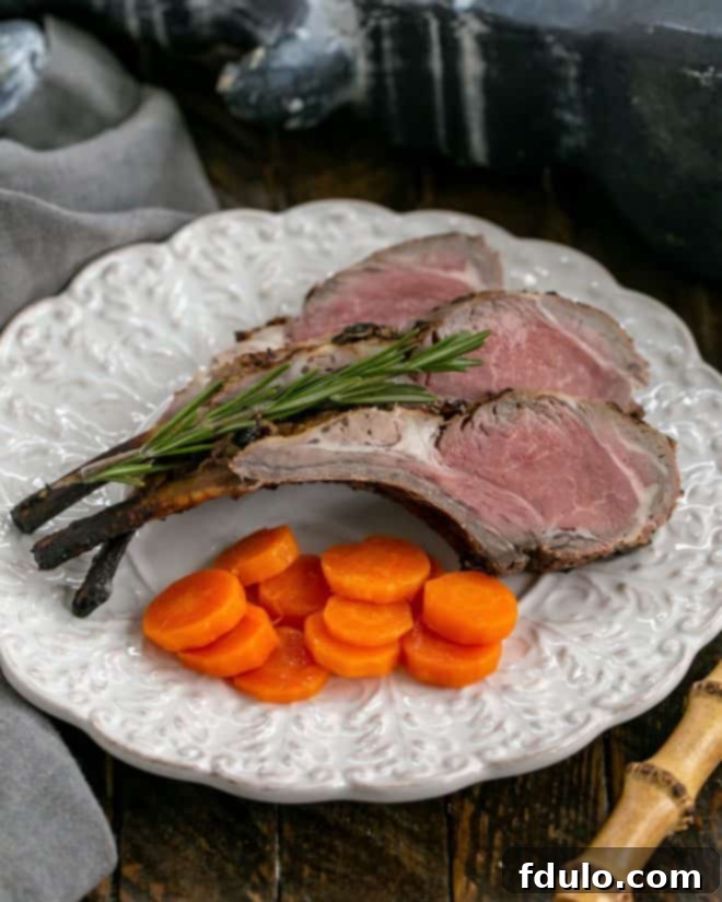 Overhead view of grilled lamb chops artfully arranged on a white decorative plate, garnished with a sprig of fresh rosemary and vibrant carrot coins, showcasing their golden-brown crust.