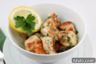 Close-up of golden brown chicken pieces in a skillet with herbs