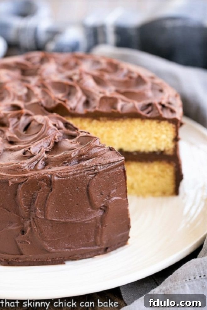 Perfect Yellow Cake Recipe with Chocolate Buttercream on a white cake plate with a slice removed