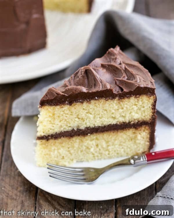 Slice of Perfect Yellow Cake Recipe with Chocolate Buttercream on a white cake with a red handled fork.