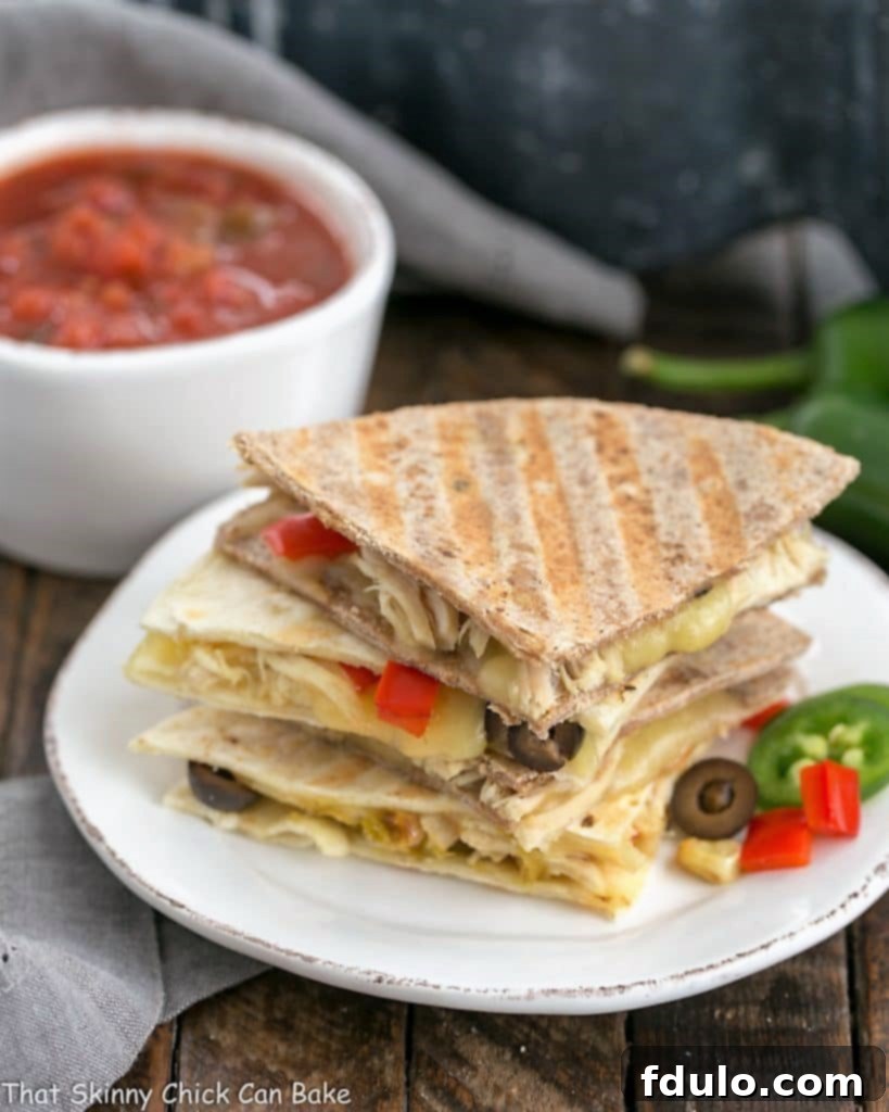 Cheesy Chipotle Chicken Quesadillas stacked on a round white plate, garnished with fresh cilantro.