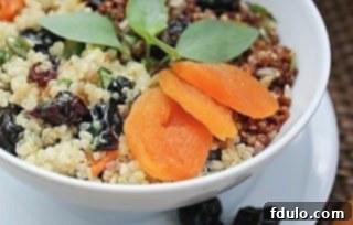 Close up of Quinoa, Fruit and Nut Salad in a white bowl on a white plate