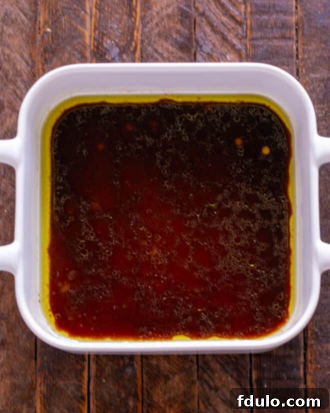 A bowl containing a rich, amber-colored marinade, ready for the salmon.