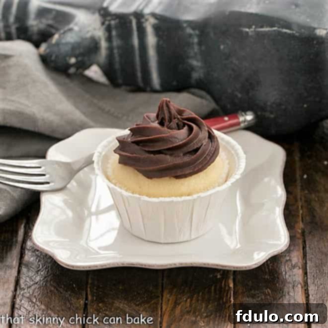 A boston Cream Pie Cupcake on white square plate with a red handled fork