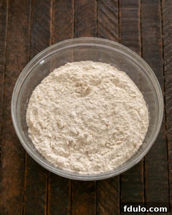 Cold butter being rubbed into the dry mixture until it resembles cornmeal.