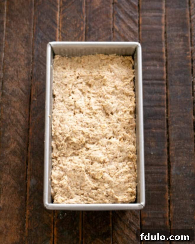 Dough for Irish Brown Bread being scraped into a prepared loaf pan.