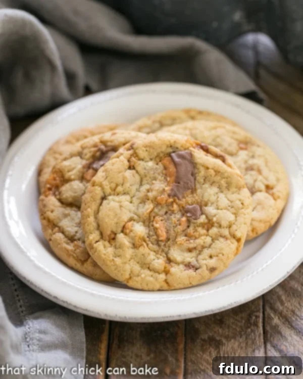 A selection of golden-brown Chewy Butterfinger Cookies artfully arranged on a pristine round white plate, ready to be enjoyed.