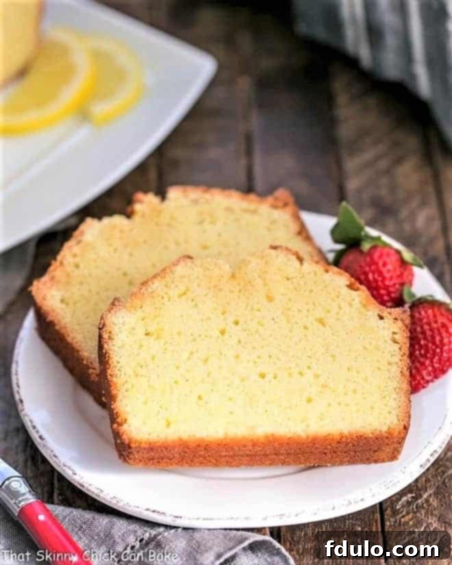 Three slices of Glazed Lemon Pound Cake garnished with fresh berries and mint leaves, ready to be served.