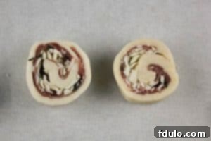 Unbaked Prosciutto Gruyère Pinwheels ready for the oven Prosciutto Gruyère Pinwheels arranged on a baking sheet before baking, showcasing the filling