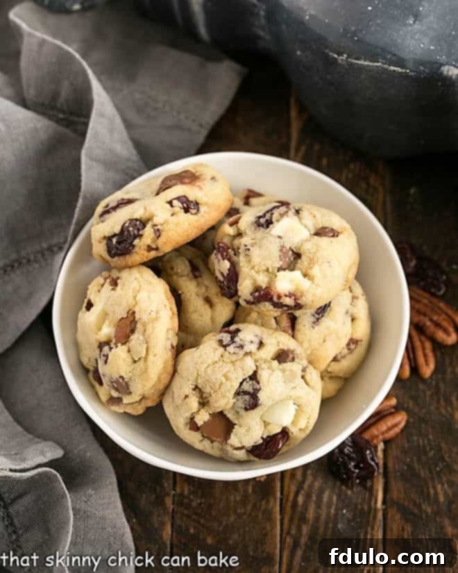 Overhead view of a small bowl full of chocolate chunk cookies, garnished with fresh cherries.