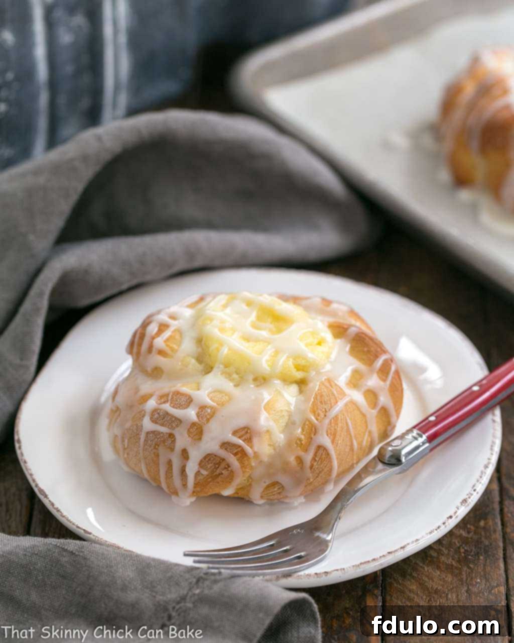 Cream Cheese Danish - tender, sweet yeast bread danish twists with a luscious cream cheese filling Danish Twists with Cream Cheese Filling on a white plate with a red handled fork.