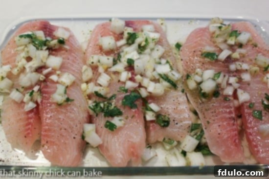 Close-up of fresh white fish marinating in a citrus and herb mixture in a glass baking dish, ready for grilling.