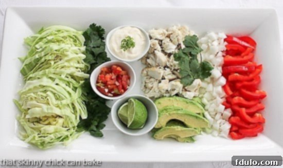 A vibrant platter featuring grilled fish tacos components: flaky fish, colorful cabbage, creamy avocado, and zesty sauces.
