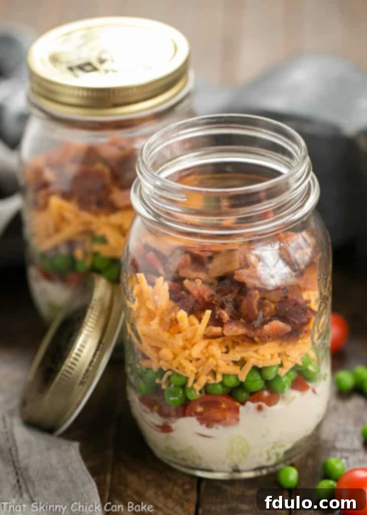Two Make Ahead 7-Layer Salads in a Jar, one with the lid off