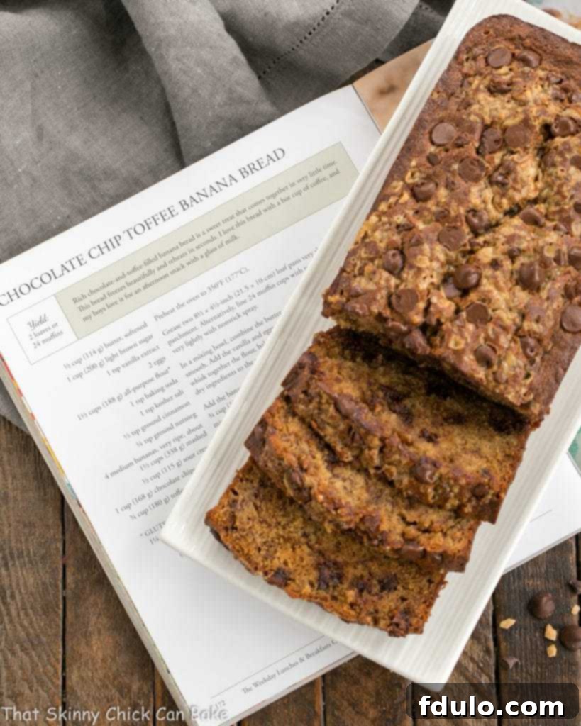 Chocolate Chip Toffee Banana Bread sliced, on a white platter, resting on a cookbook