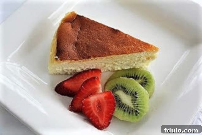 Slice of creamy Ricotta Cheesecake with Homemade Ricotta on a white plate, garnished with lemon zest